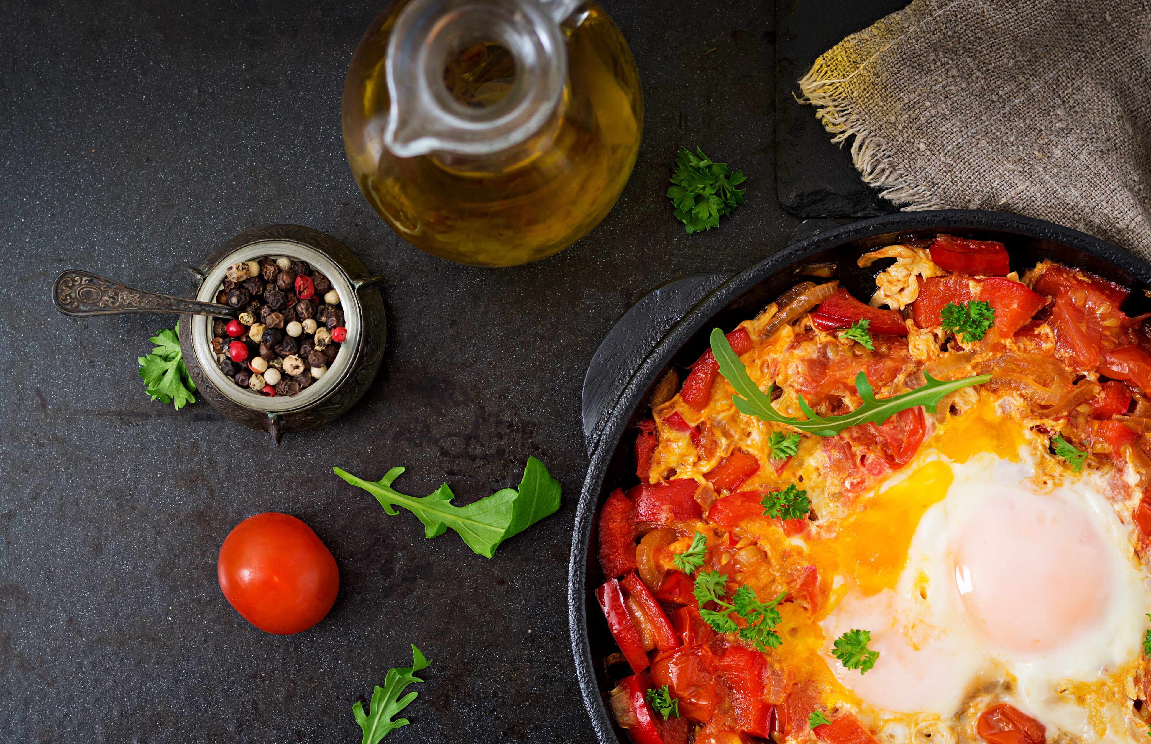 Fried eggs with vegetables - shakshuka in a frying pan on a black background in the Turkish style. Flat lay. Top view;